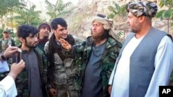 A foreign Islamic State group fighter (2nd right) speaks to a journalist after he surrendered to government security forces in the Darzab district on August 1.