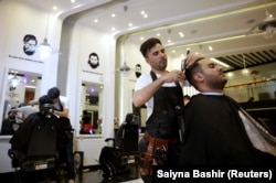 A barber gives a customer a haircut at a hair salon in Kabul.