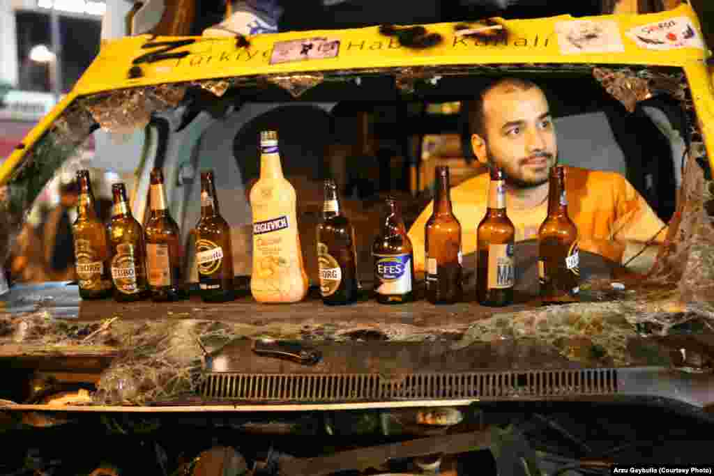 A fan relaxes in a burned-out minibus. Beer is a hot commodity in the square, where many protesters are angry that Turkish Prime Minister Recep Tayyip Erdogan has tried to restrict alcohol sales. A popular chant involves a satirical toast to the prime minister.