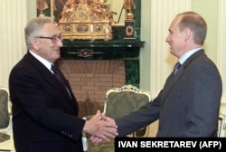 Russian President Vladimir Putin shakes hands with Kissinger during their meeting in Moscow on July 13, 2001.