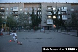 A boy plays soccer in a courtyard in Ulken.