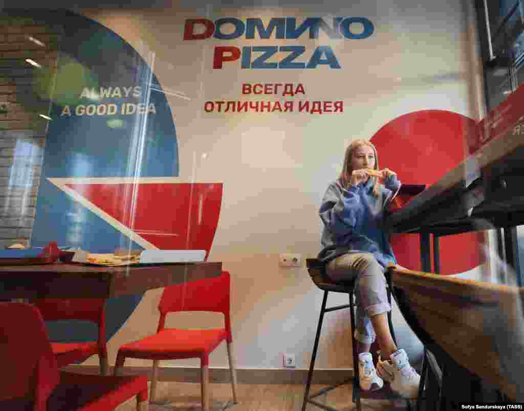 A woman enjoys a slice in a rebranded Domino&#39;s Pizza outlet in Moscow that was reopened on August 30 as &quot;Domиno Pizza,&quot; with the Latin &quot;i&quot; in the name replaced with the equivalent Cyrillic letter &quot;и.&quot;