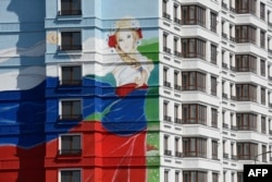 A newly built residential building in Mariupol features an image of a girl wearing a dress painted in the colours of the Russian flag in August 2023.