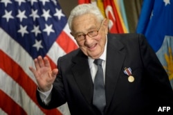 Kissinger waves after receiving an award during a ceremony at the Pentagon honoring his diplomatic career on May 9, 2016.