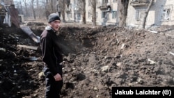 A man in Avdiyivka inspects a fresh crater after Russian shelling in the center of his hometown.