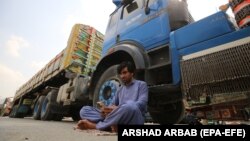 A driver sits beside his parked truck, carrying goods destined for Afghanistan, waiting for the opening of the border following clashes between the security forces of Pakistan and Afghanistan, in Torkham, Pakistan, on September 7.