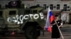 A man holds the Russian flag in front of a Wagner Group military vehicle painted with the word "Rostov" in Rostov-on-Don late on June 24.