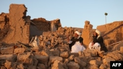 Afghan men sit beside a damaged house after an earthquake in Afghanistan's Herat Province on October 7.