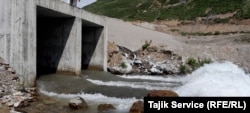 Large hoses connected to the discharge pools from the Pokrud gold mine can be seen feeding into the river, where they emit white runoff into the water. (June 2023)