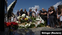 Mourners stand next to the grave in Lviv of Svitlana Lukyanchuk, a 30-year-old physician who was killed in the suspected Russian missile strike on Kyiv's Okhmatdyt children's hospital.