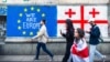 People walk past Georgian and EU flags painted on the wall in Tbilisi.