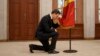 Moldovan Prime Minister Dorin Recean kneels in front of the national flag during a swearing-in ceremony in Chisinau on February 16.