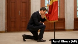 Moldovan Prime Minister Dorin Recean kneels in front of the national flag during a swearing-in ceremony in Chisinau on February 16.