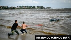 People try to pull out a car submerged in the sea at a camping site near Tsarevo on the Bulgarian Black Sea coast on September 6. 