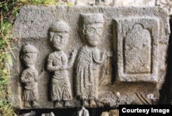 A file photo of the carving depicting the church builders holding the church plan.