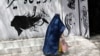 An Afghan woman walks past a beauty salon in Kabul.