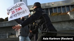 Police officers restrain a protester during a rally of journalists against a new media bill in front of the parliament building in Baku in December 2021.