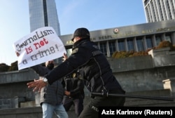 Police officers restrain a protester during a rally of journalists against a new media bill in front of the parliament building in Baku on December 28, 2021.