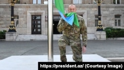 Azerbaijani President Ilham Aliyev raises the national flag of in Xankendi on October 15.