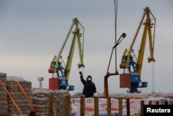 Workers unload construction supplies from a cargo vessel in the port of Mariupol in Russian-occupied Ukraine in October 2023.