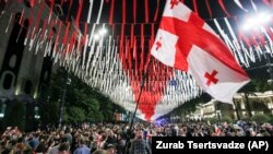 Demonstrators wave a giant Georgian national flag at the parliament building during an opposition protest against the "foreign agents" law in Tbilisi in late May.