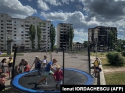 Children play against the backdrop of damaged apartment buildings in Borodyanka.