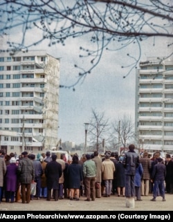 Crowds gather at the scene of an apartment collapse.