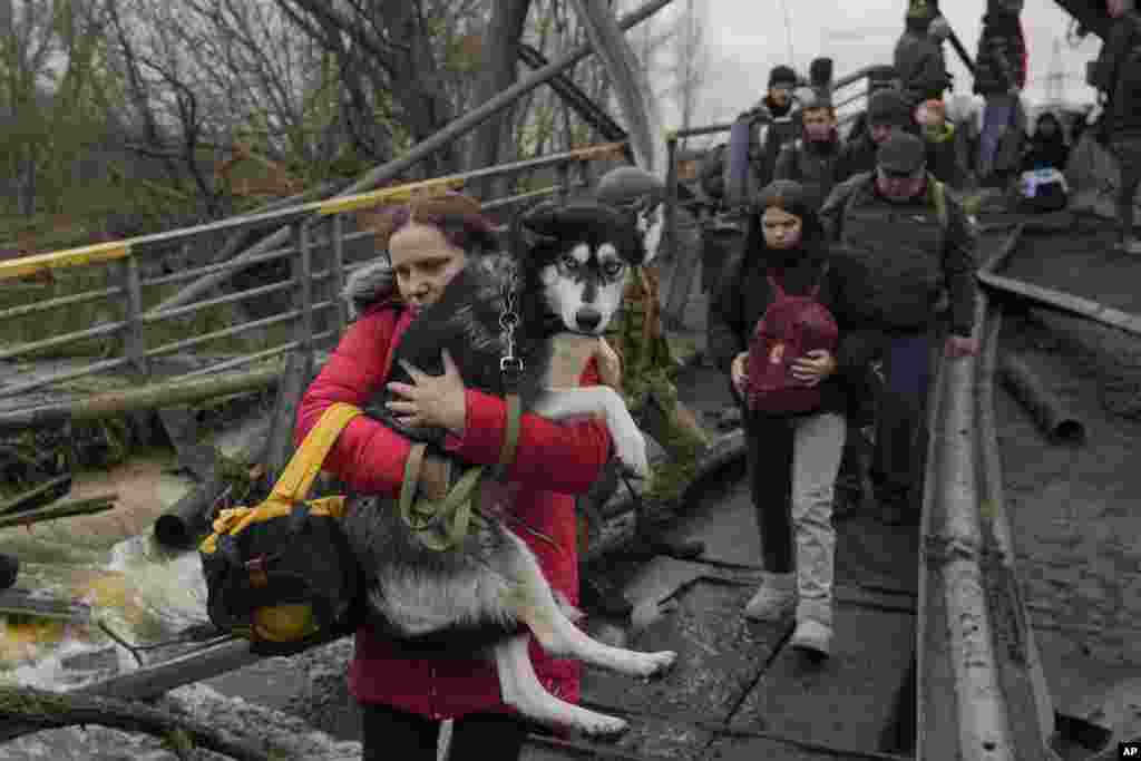 Residents of Irpin must cross a treacherous path underneath the destroyed bridge as they flee the city.