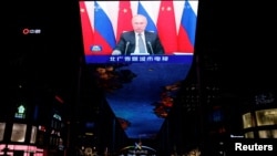 Russian President Vladimir Putin is seen on a giant screen in Beijing showing footage of a virtual meeting between him and Chinese President Xi Jinping on December 15.