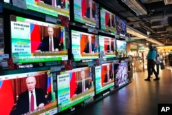 People stand by TV screens in Hong Kong broadcasting the news that Russian troops have launched an attack on Ukraine on February 24.