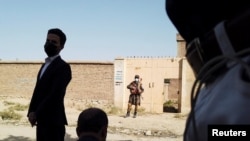 A Taliban soldier stands guard in front of a house neighboring a IS-K hideout raided by Taliban forces in northern Kabul in early October.