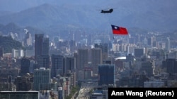 A Taiwanese flag is carried by a Chinook helicopter during a rehearsal for the Island’s National Day celebration in Taipei on October 7.