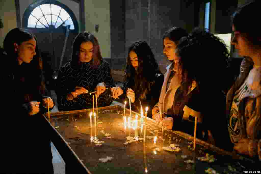 Members of Asparez, a dance group from Stepanakert, light candles in a church in Goris. The teenagers were traveling with their teacher, Lari Avanesian (second from left), to compete in a dance contest in Tbilisi, when the road back to their homes was shut.