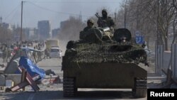 Russia-backed troops in uniforms without insignia drive an armored vehicle in the besieged Ukrainian port city of Mariupol on March 19.