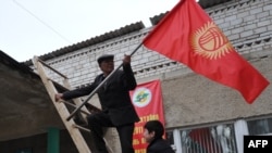 People fix national flags atop a local polling station in the Besh-Kungey village outside the Kyrgyz capital, Bishkek.