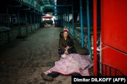 A woman kneels by her dead husband after Russian shelling in Kherson on December 24.