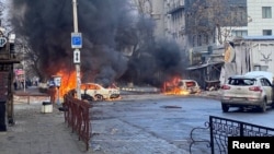 Cars burn on a street after a Russian military strike in Kherson, Ukraine, on December 24.
