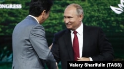 Japanese Prime Minister Shinzo Abe (left) shakes hands with Russian President Vladimir Putin during a session of the Eastern Economic Forum in Vladivostok on September 12.