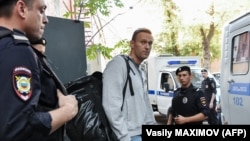 Russian opposition leader Aleksei Navalny is escorted by police after his trial at a Moscow courthouse on August 27.