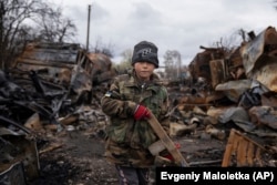 Seven-year-old Yehor holds a wooden toy rifle next to destroyed Russian military vehicles near Chernihiv on April 17.