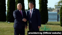 Hungarian Prime Minister Viktor Orban (left) and Kyrgyz President Sooronbai Jeenbekov shake hands on September 3.