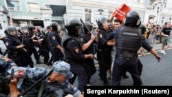 Police and servicemen of the Russian National Guard detain protesters during a rally against planned increases to the pension age in Moscow on September 9.