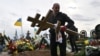 A worker carries a cross at the funeral of Mykhaylo Matyushenko, a colonel of Armed Forces of Ukraine who was shot down in the sky over the Black Sea on June 26, at a cemetery of Bucha, Ukraine, on October 3.