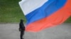 A Russian policeman stands guard at a polling station beneath a Russian flag in Ukraine's Luhansk region on September 27. 