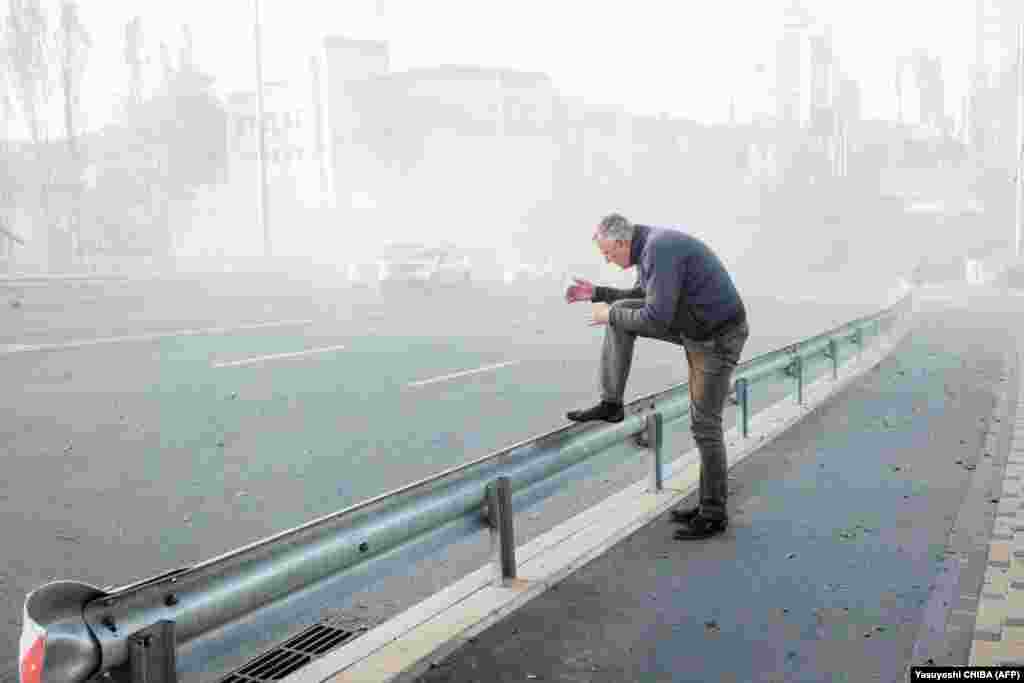 A man is surrounded by dust near the site of a drone attack.