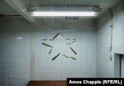 An art display of bullets hanging from threads inside a room in the bunker