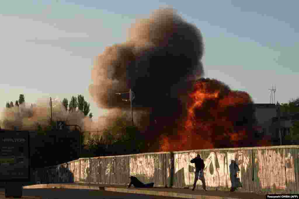 A man is seen falling to the ground in Kyiv as another runs away from the impact of a Russian strike.