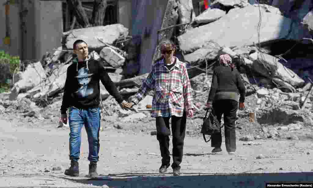 A couple walk hand in hand through a destroyed residential area on May 12.