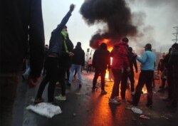 Iranian protesters gather around a fire during a demonstration against an increase in gasoline prices in Tehran on November 16, 2019.