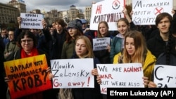 Protesters hold posters reading: "What did we spill our blood for?", "No capitulation", "Crimea, Donbas, Ukraine" as they gather in Independence Square in Kyiv on October 6 to rally against any concessions to Russia.